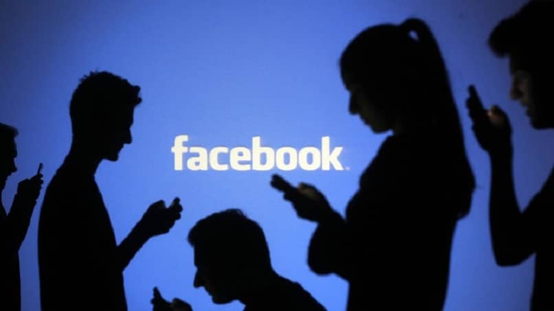 logo facebooka z ludźmi i telefonami komórkowymi podłączonymi do sieci