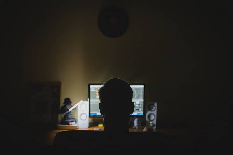 mężczyzna patrzy na światło monitora w ciemnym pokoju
