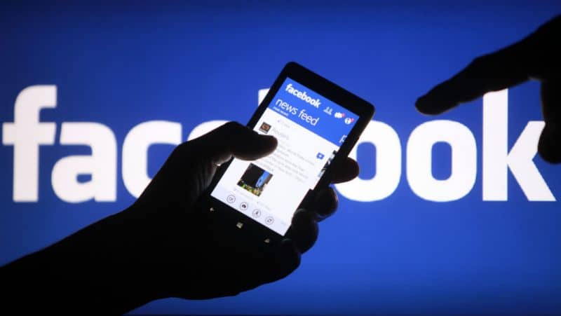 Facebook, mężczyzna z telefonem komórkowym w dłoni