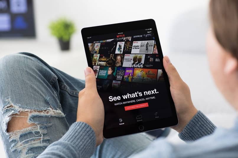 osoba siedząca z tabletem w dłoni i oglądająca katalog Netflix