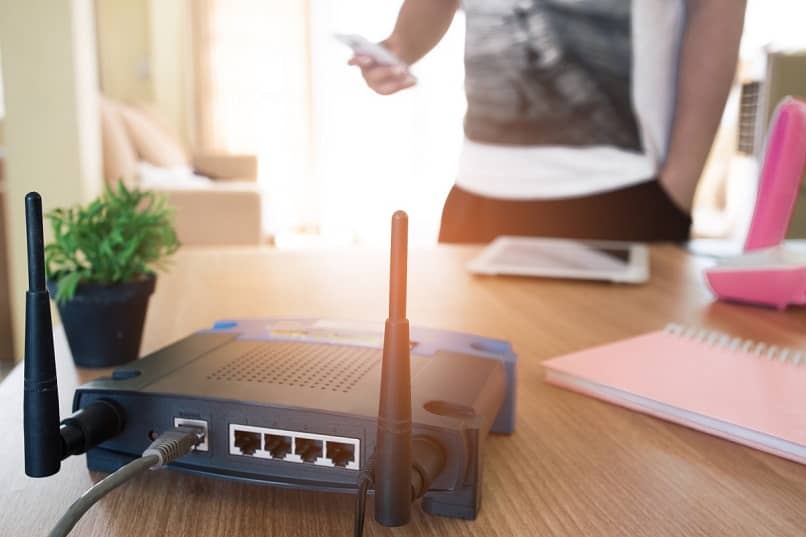 zdjęcie czarnego routera z szarym kablem przekazującym sygnał wifi do urządzenia mobilnego