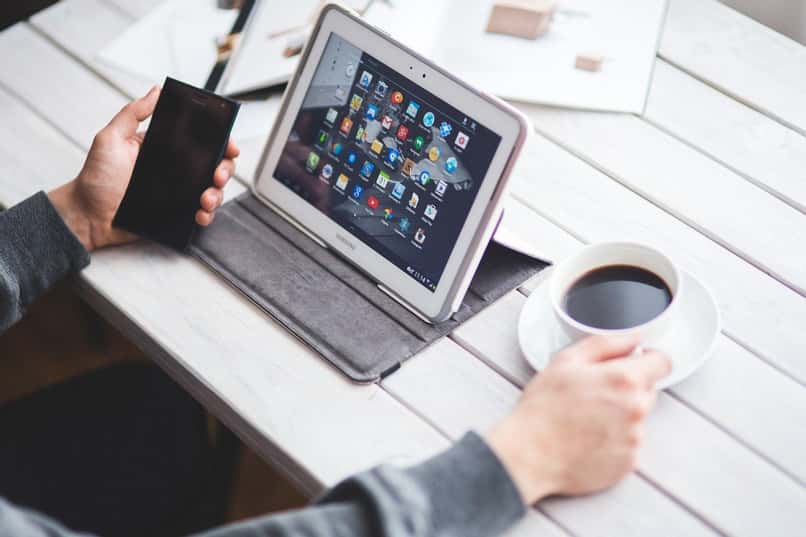 osoba używa tabletu z Androidem i trzyma filiżankę kawy