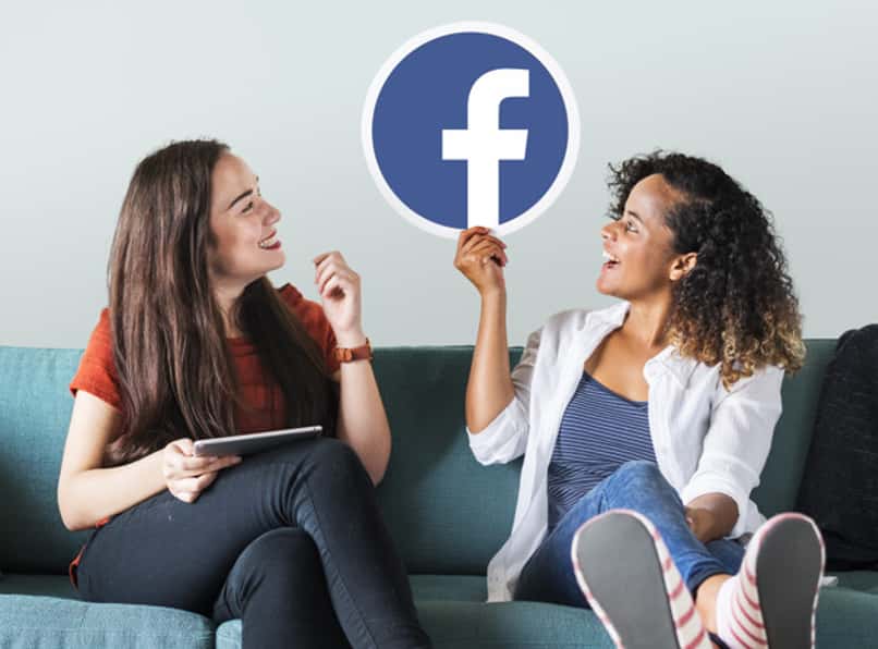 dwie kobiety trzymające logo facebooka