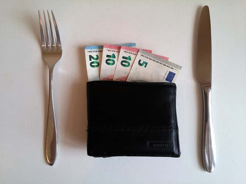 pieniądze i portfel na stole ze sztućcami