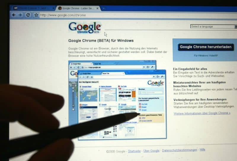 ekran komputera z Google Chrome i dłońmi wskazującymi ołówkiem