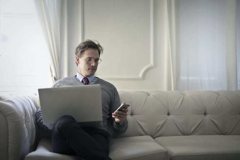 mężczyzna siedzący przy użyciu komputera i telefonu