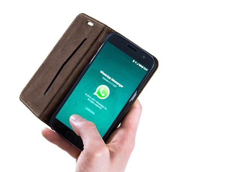 użytkownik manipuluje telefonem ręką podczas otwierania WhatsApp