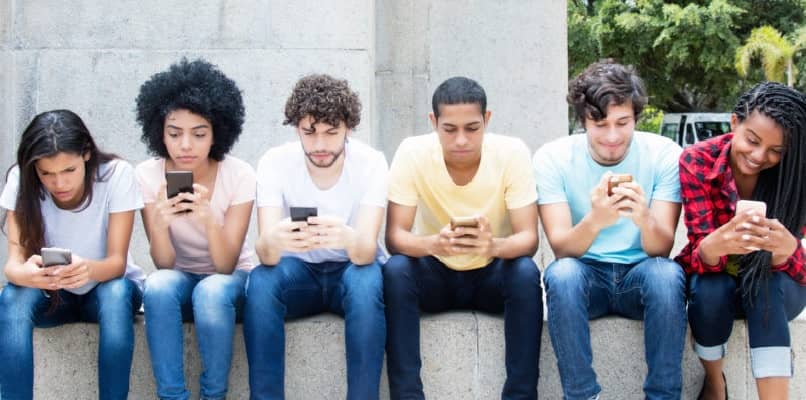 grupa młodych ludzi patrząca na swoje telefony