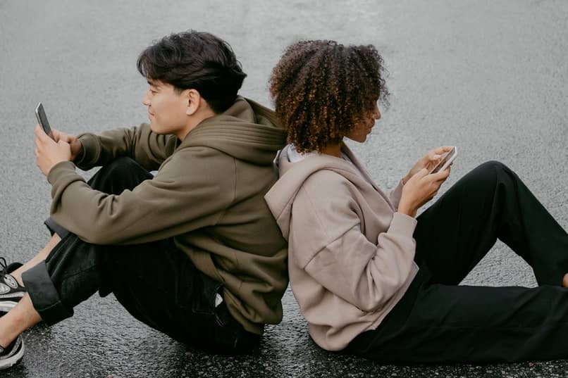 młodzi ludzie siedzący przy użyciu telefonów komórkowych