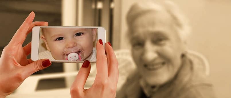 dziecko na ekranie telefonu komórkowego ze staruszką w tle